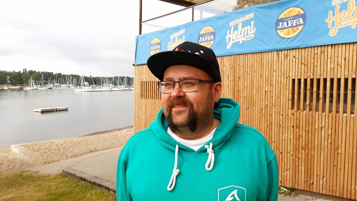 Mies seisoo rantakahvilansa edessä rannan äärellä.