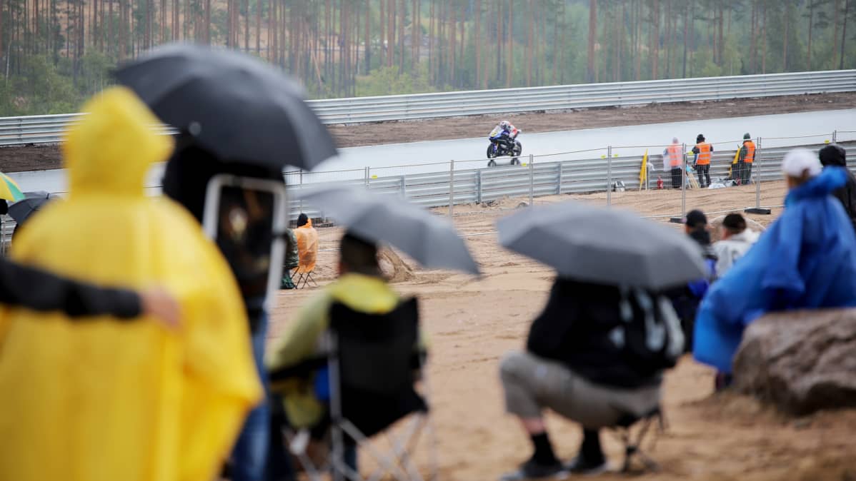 Katsojat seuvaaravat sateenvarjojen alla Kymi Ringin testiajoa
