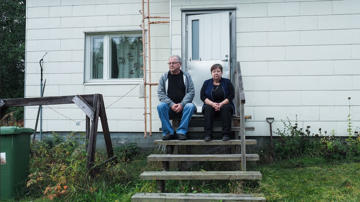 Leena ja Ismo Kilpeläinen istuvat talon portailla.
