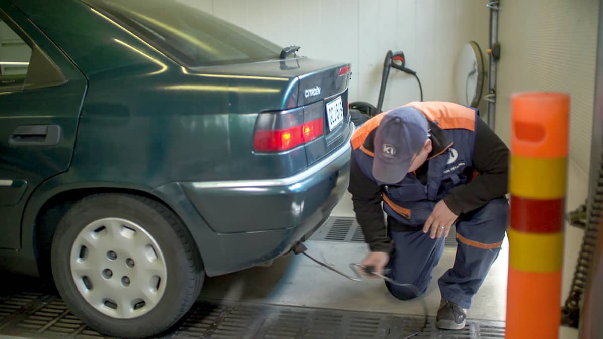 Katsastusmies työntää vihreän Citroen Xantian pakoputkeen mitta-anturia Sarankulman K1-katsastusasemalla Tampereella.