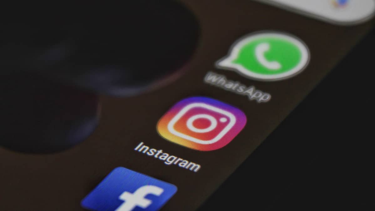 Puhelimen näytöllä näkyvät Facebookin, Instagrammin ja WhatsAppin ikonit.