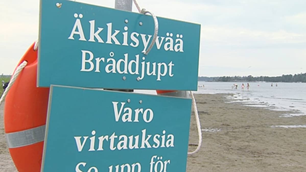 Pelastusrengas ja varoituskylttejä uimarannalla