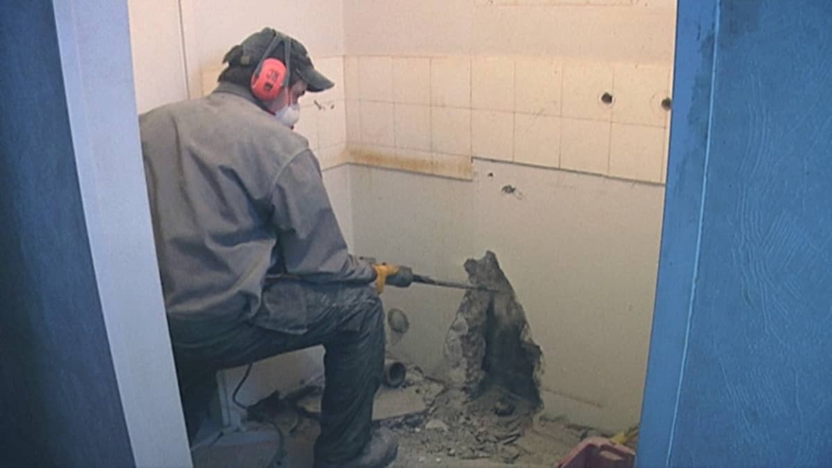 Rakennusmies piikkaa kylpyhuoneen seinää