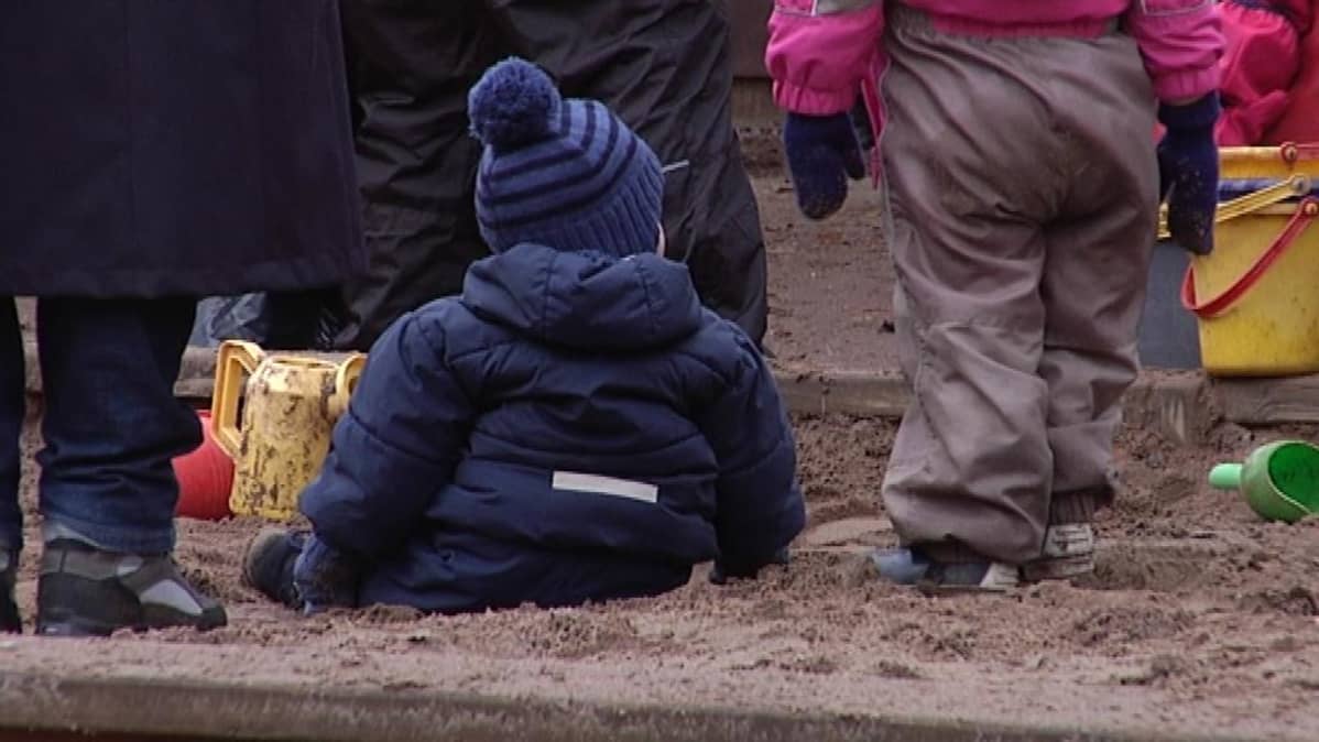 Lapsi istuu hiekkalaatikolla.