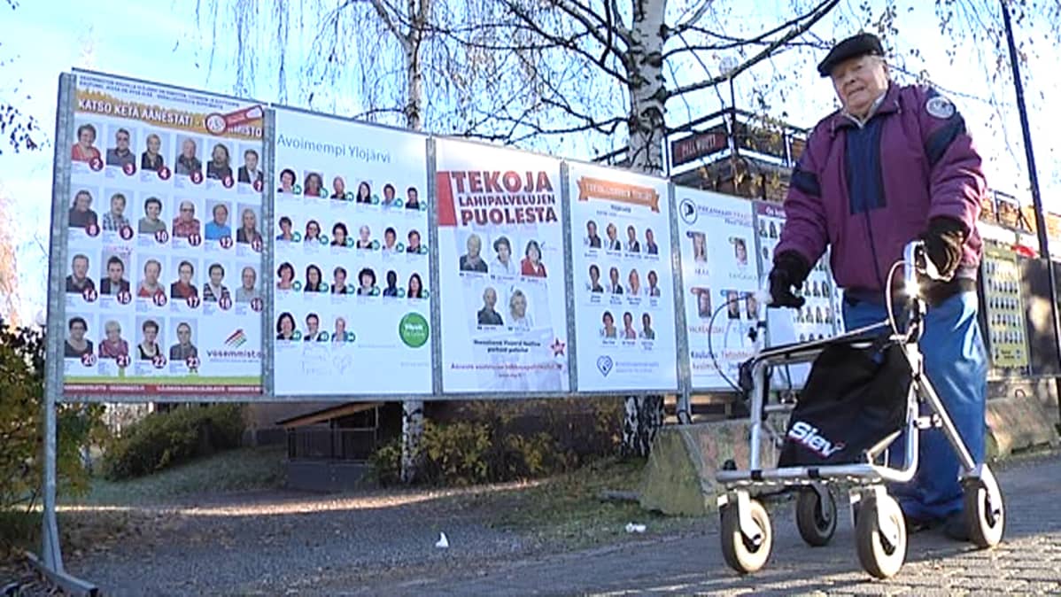 Vanha mies menee rollaattorin kanssa vaalimainosten ohi Ylöjärvellä.