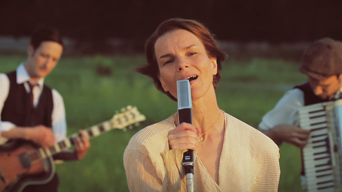 Laulaja Anna Järvinen musisoi laskevan auringon punertavassa valossa.