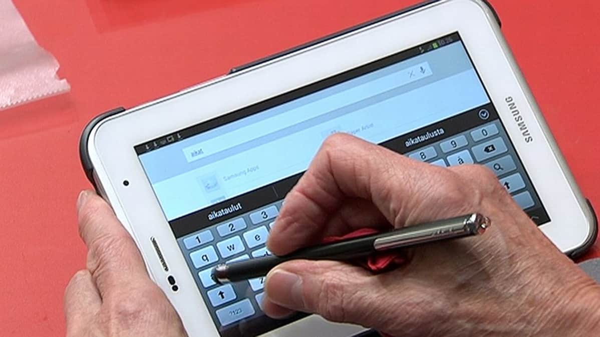 Henkilö käyttämässä tablettia.