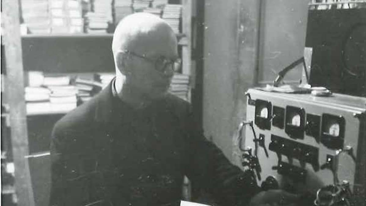 Kuvassa tuntematon mies radiokaitteen äärellä