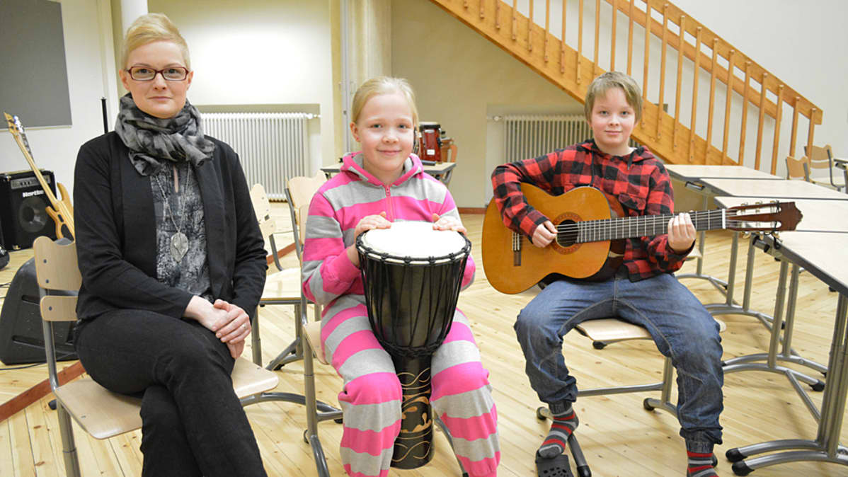 Kajaanin Keskuskoulun musiikkiluokan opettaja Paula Hänninen poseeraa yhdessä musiikkiluokkalaisten Juho Partasen ja Inka Hyrkäksen kanssa.