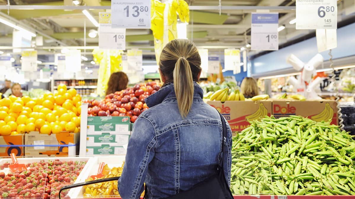 Nainen ruokakaupan vihannestiskillä.