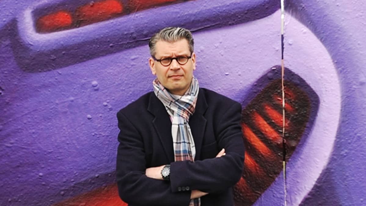 Tutkija Mika Helin graffitiseinä takanaan.