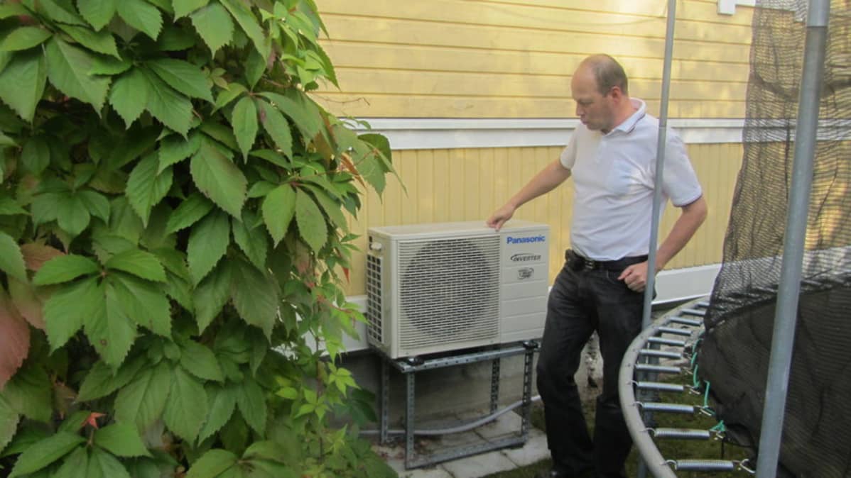 Mikko Nurhonen katselee ilmalämpöpumppuaan.