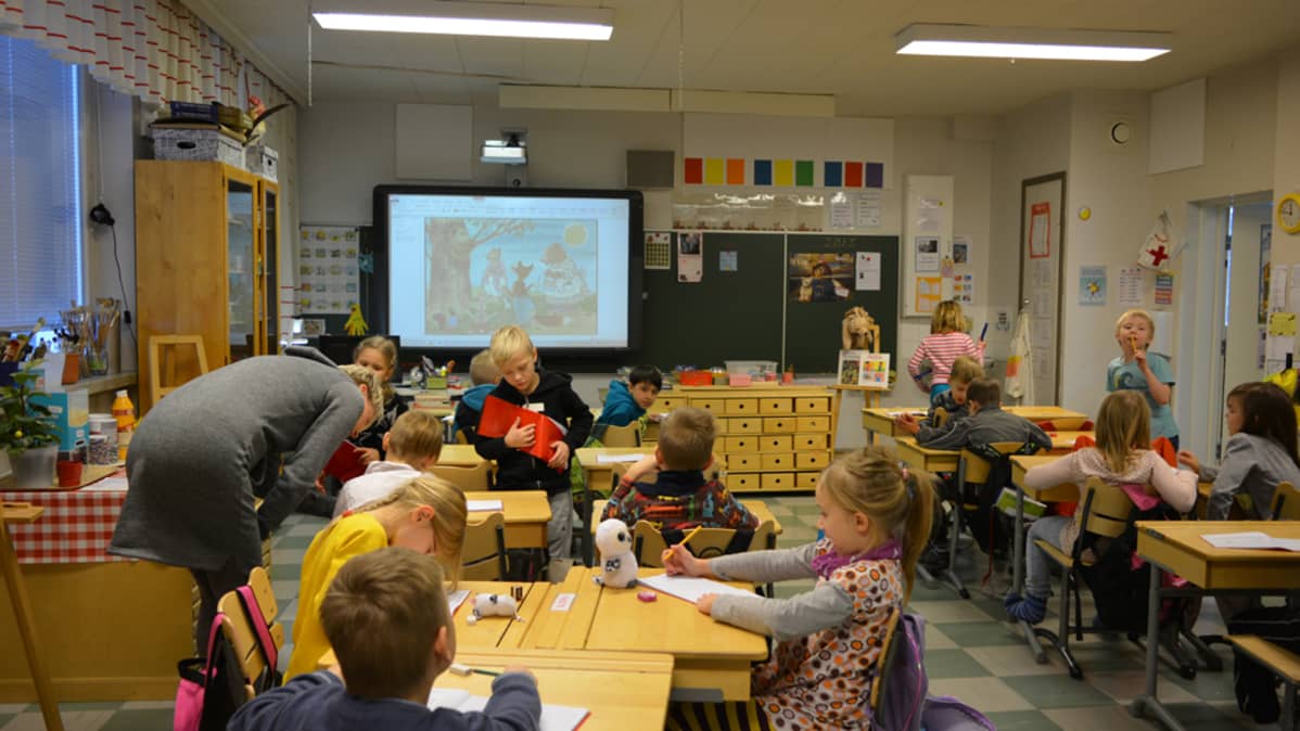 Kajaanin Teppanan koulun ekaloukkalaiset istuvat luokkahuoneessaan ja tekevät vihkoon kirjoitustehtäviä.