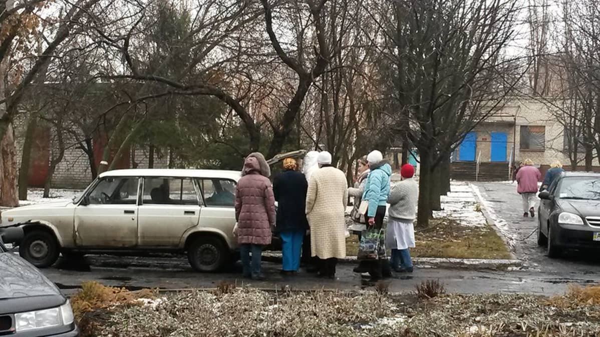 Ihmisiä jonottamassa autoon josta myydään maitotuotteita.