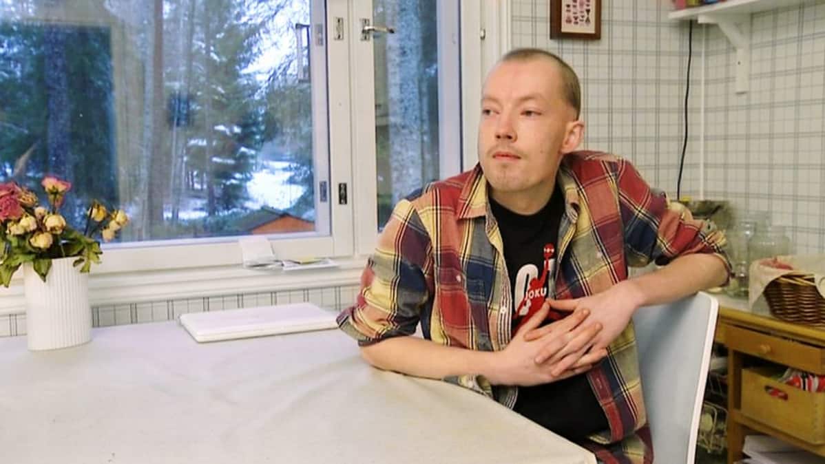 Mies istumassa pöydän ääressä.