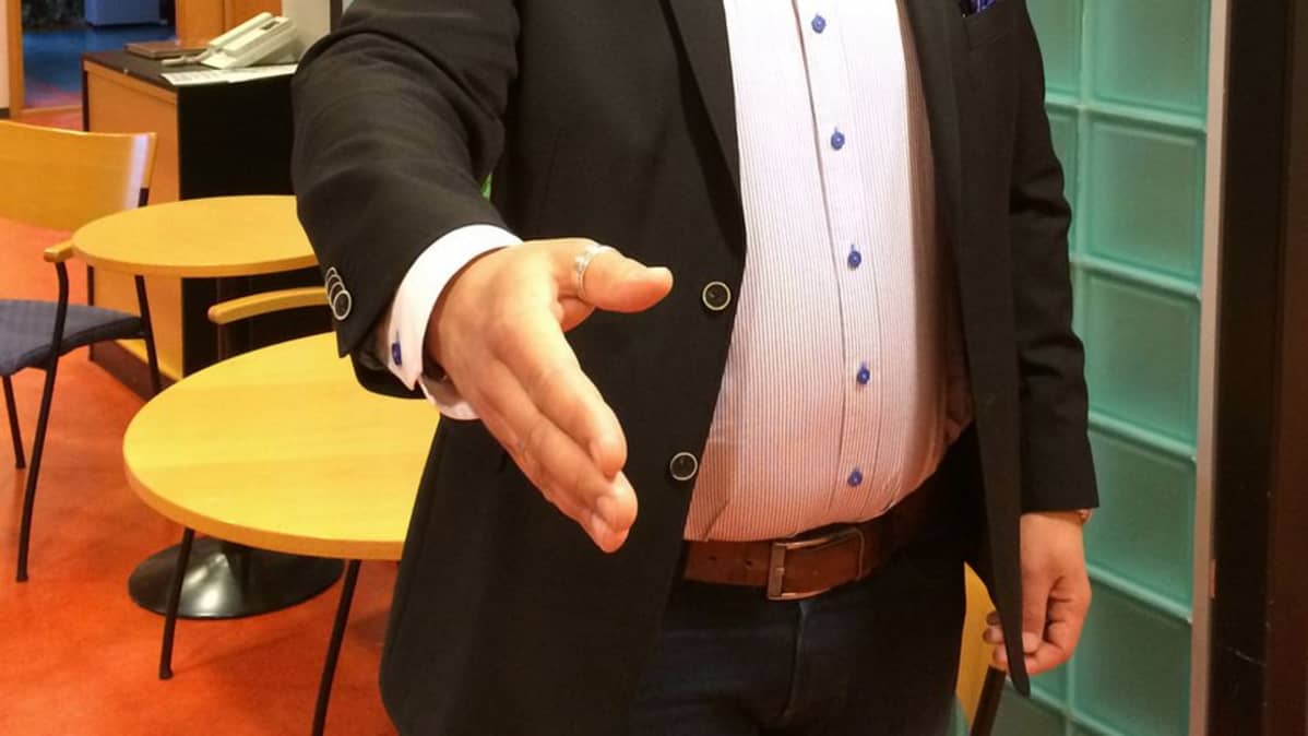 Mies ojentaa käden kättelyä varten.