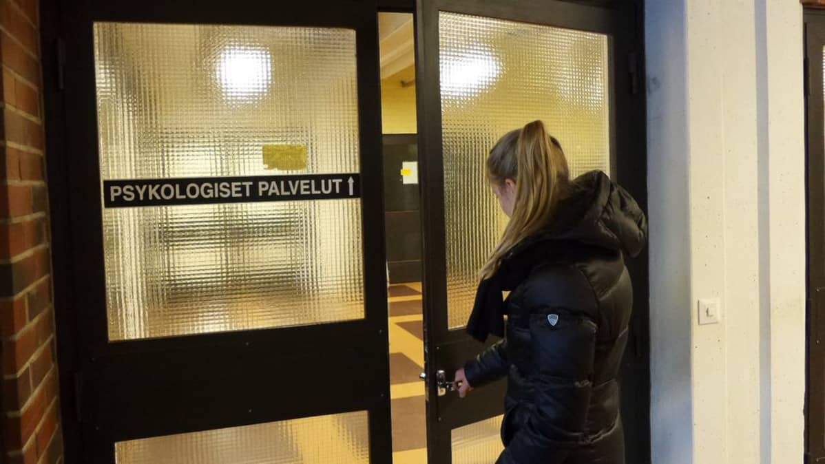 Nuori nainen avaamassa terveyskeskuksen ovea.