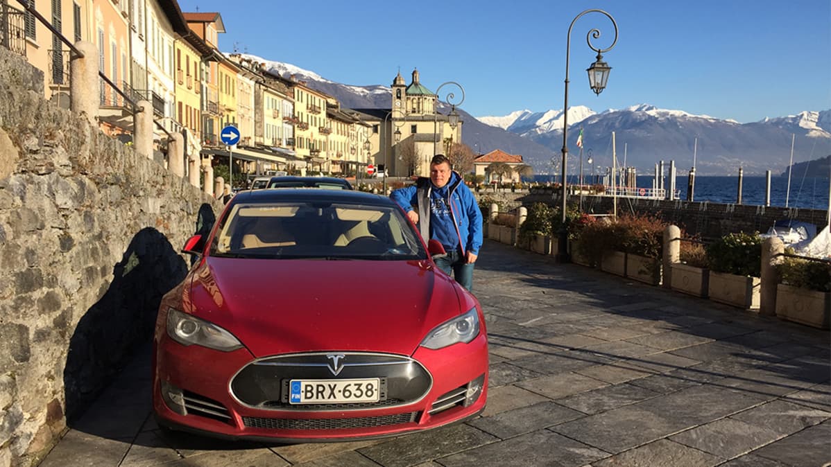 Mies ja punainen Tesla-sähköauto.
