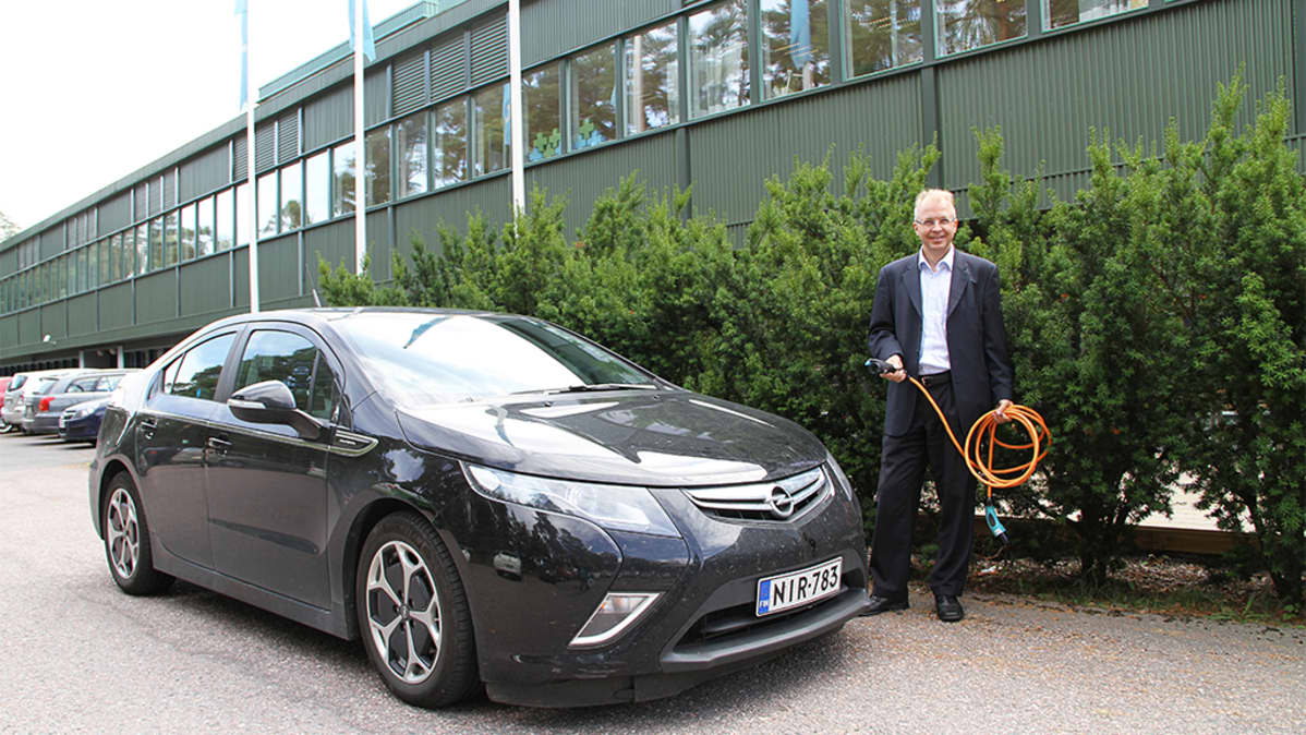 Sähköauto ja mies laturijohdon kanssa.