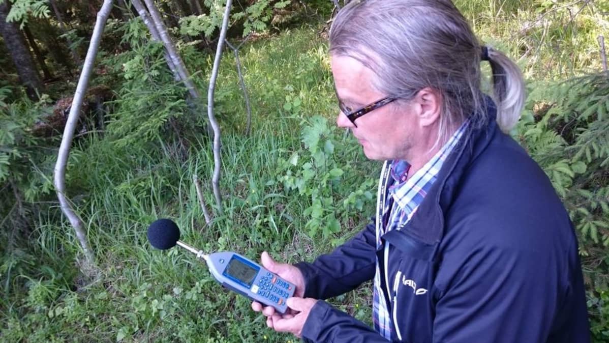 Ilkka Niskanen mittaa melumäärä mittarilla luonnossa.