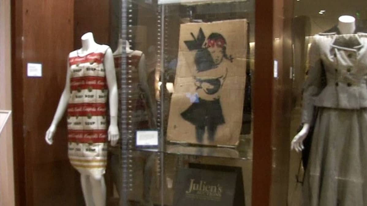 Banksyn maalaus ja muita huutokaupattavia tavaroita esillä Julien's-huutokauppakamarilla.
