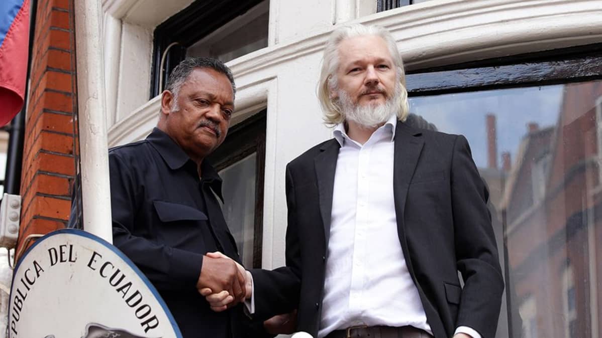 Julian Assange pastori Jesse Jacksonin kanssa Ecuadorin suurlähetystön parvekkeella 22.8.2015.