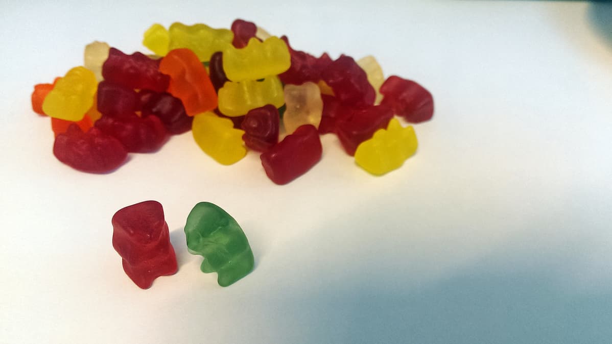 Nallekarkkeja läjässä: punainen ja vihreä nallekarkki keskustelevat.