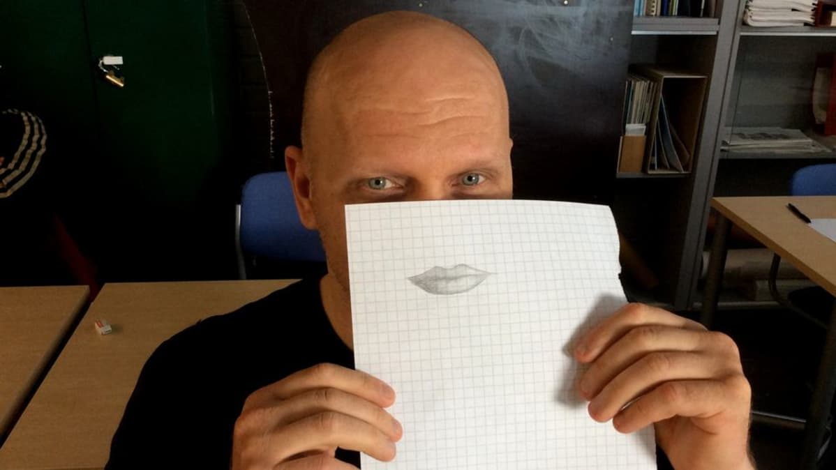 mie pitää paperia naaman edessä. Paperille piirrtetty huulet