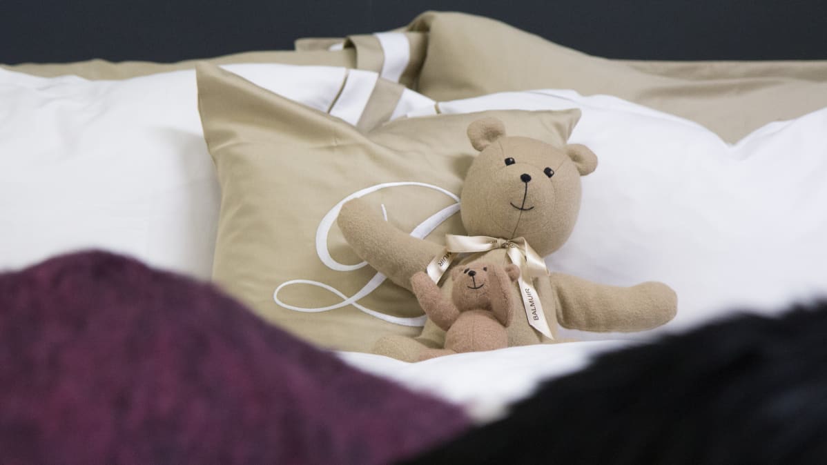Nallet nojaavat tyynyyt pedatussa vuoteessa
