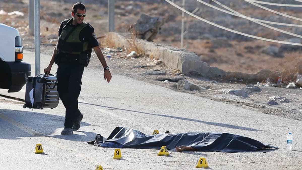 Israelilainen poliisi katselee maassa makavaa ammutun palestiinalaisen ruumista.