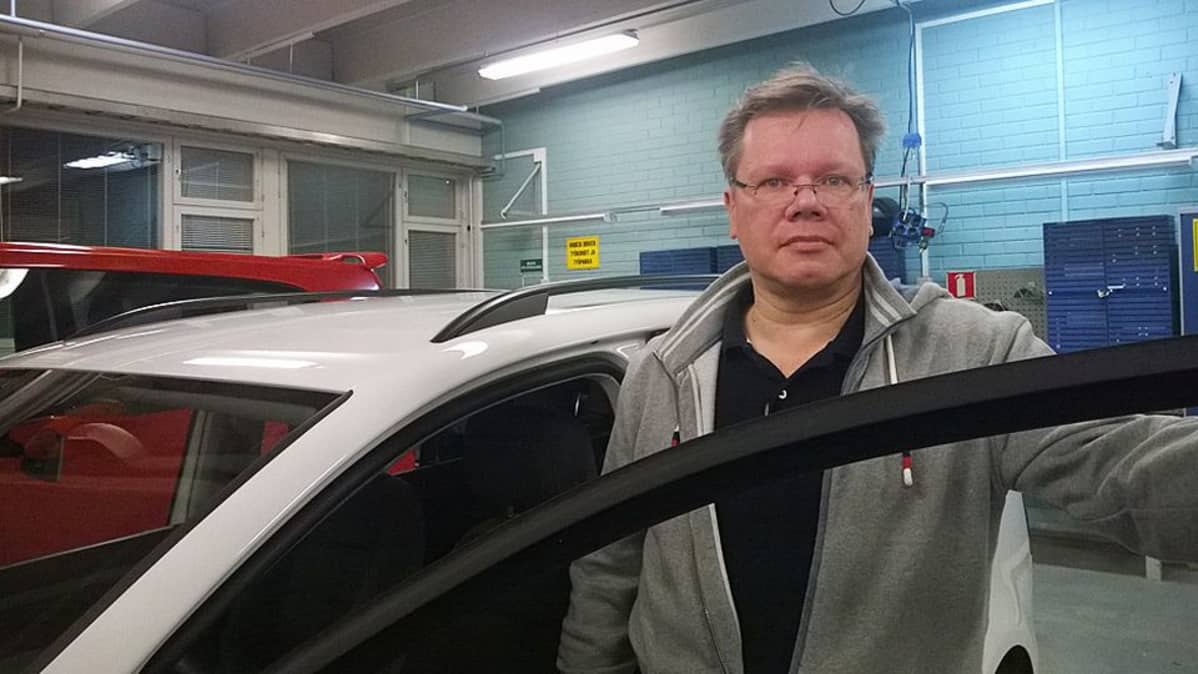 Lehtori Ari-Pekka Nieminen astuu valkoisesta autosta autotallissa.