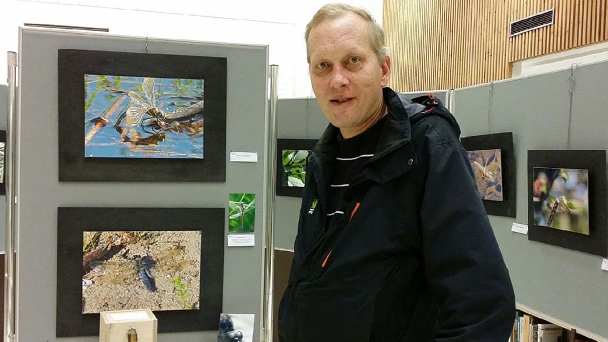 Kuvasa Jukka Mansikkamäki näyttelyssään, vieressä ja taustalla näyttelykuvia.