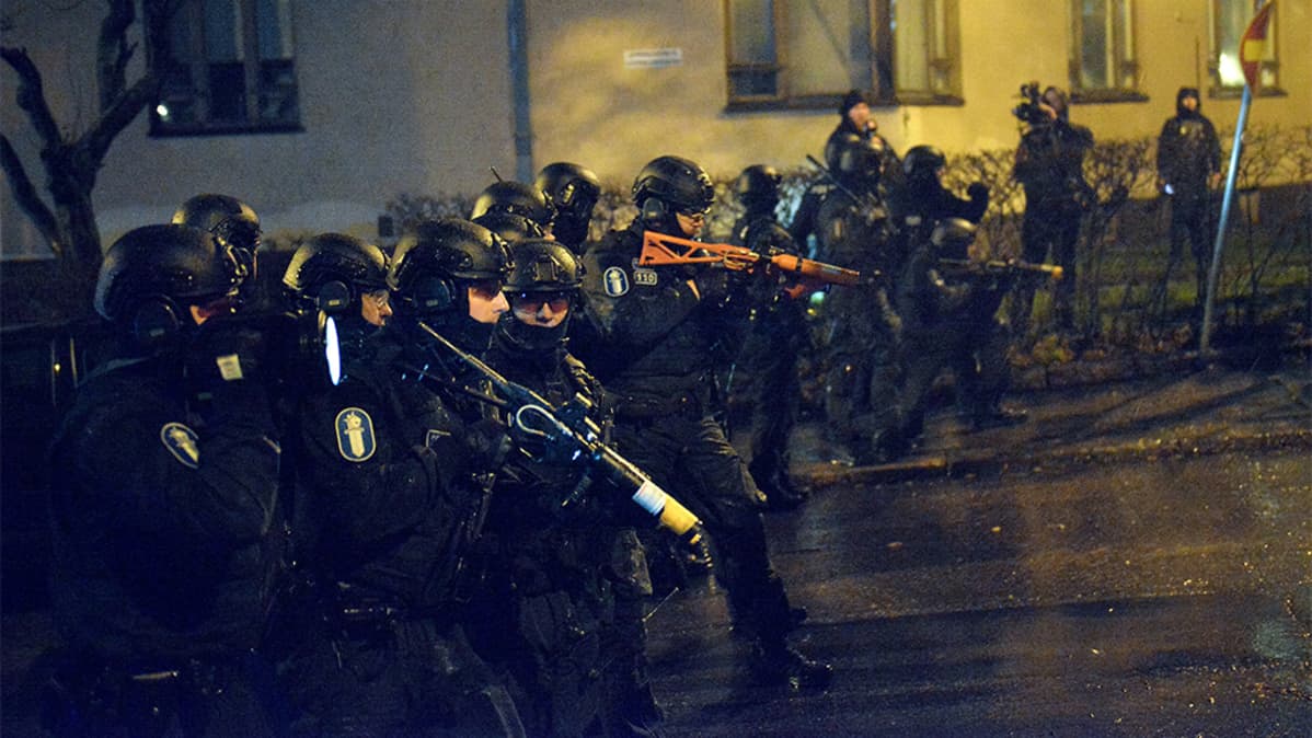 Noin viisitoista erikoisvarusteista poliisia rivissä.