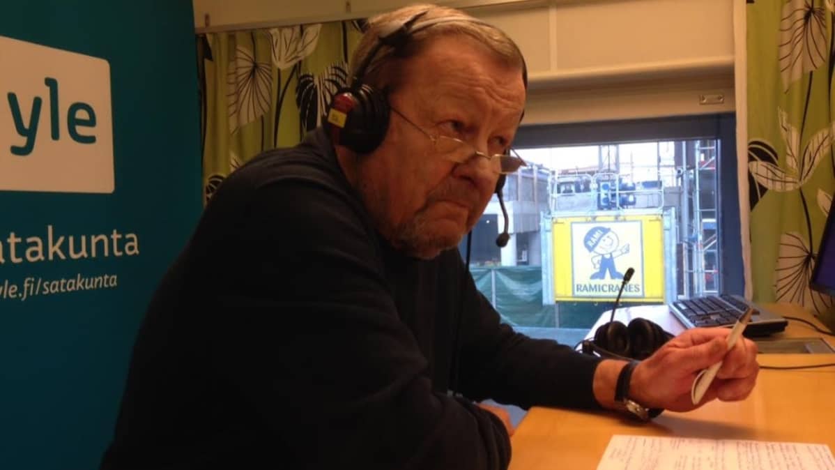 Mies Ylen studiossa kuulokkeet päässä.