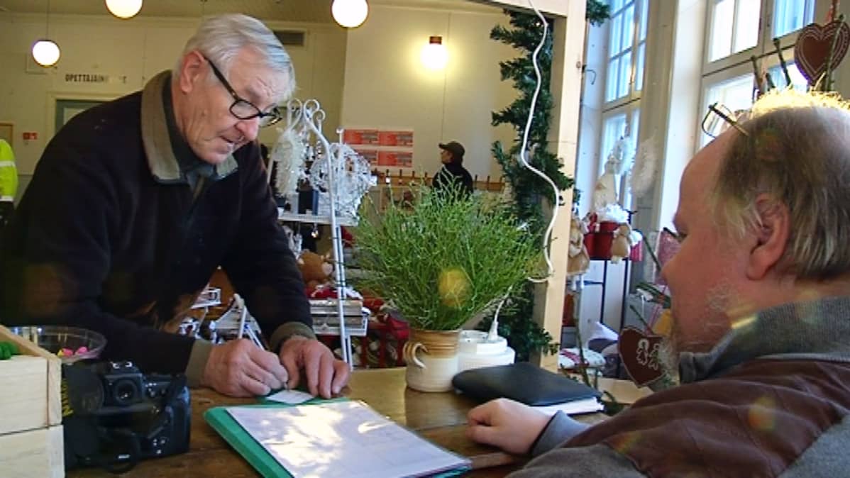Seppo Viholainen kirjoittaa viestiä hyvän tahdon puuhun Viitasaarella.