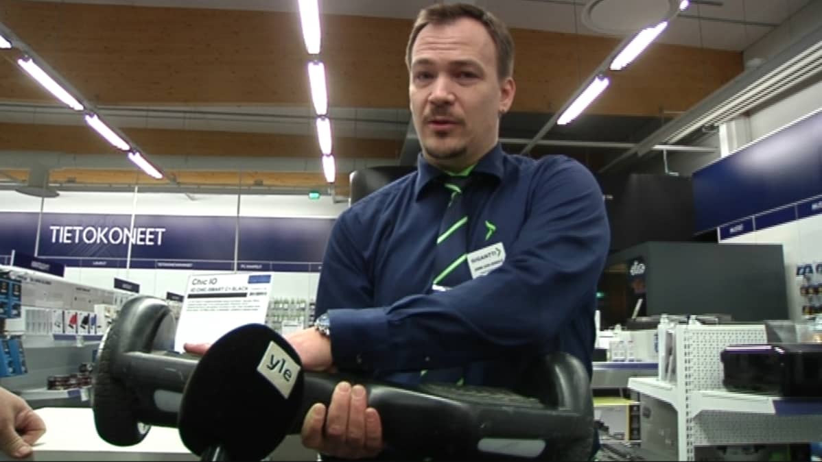 Miehellä on lauta käsissään ja hän katsoo kameraan