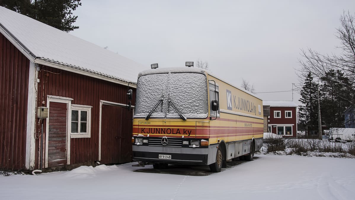 Junnolan kauppa-auto seisoo varaston vieressä.