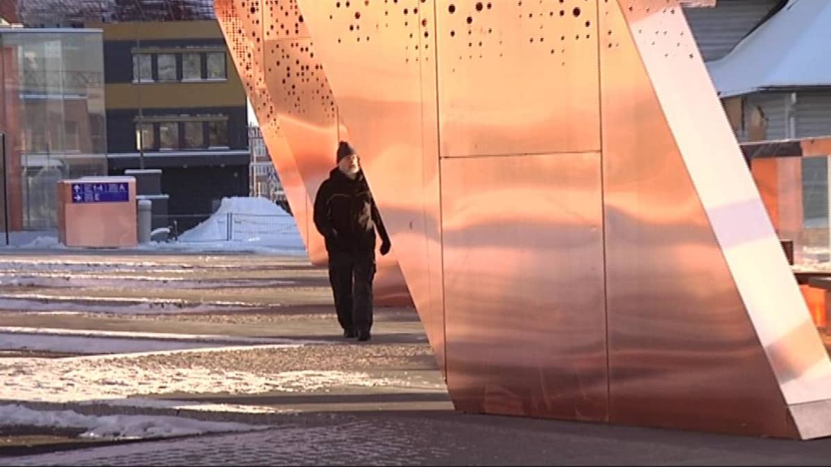 Mies kävelee kuparikatoksen alla