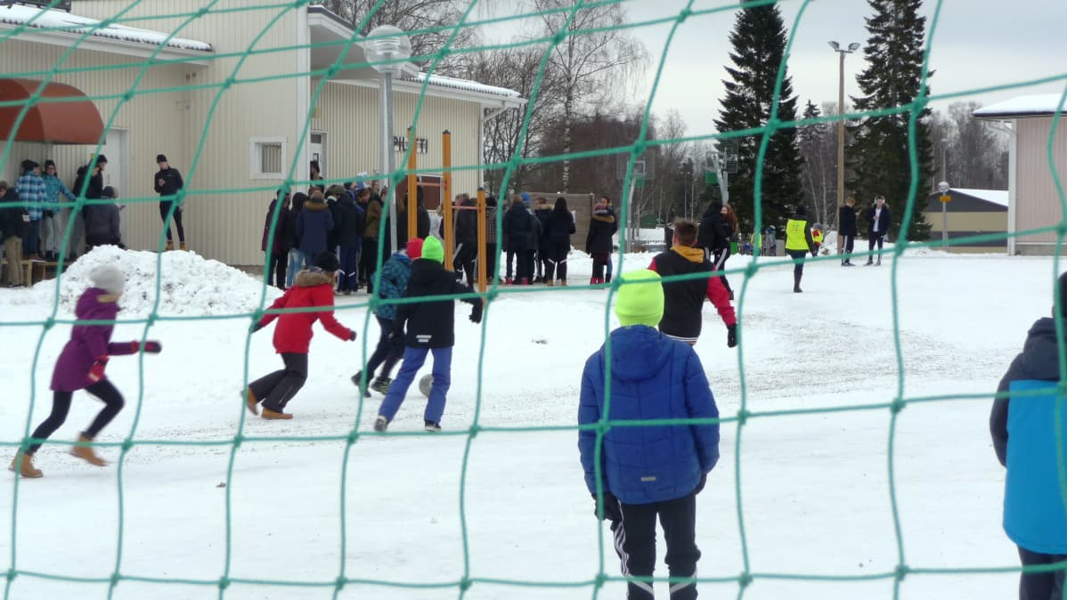 Välitunnilla pelataan jalkapalloa koulun pihalla