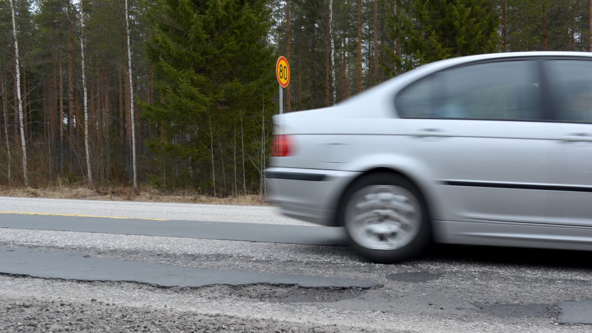 Auto ajaa huonokuntoista tietä.