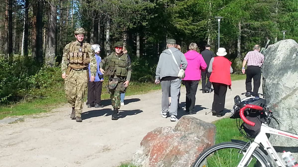Ihmisiä kävelee hiekkatietä kahteen suuntaan.