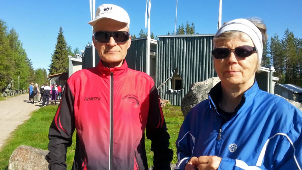 Mies ja nainen seisovat puisen rakennuksen edessä.