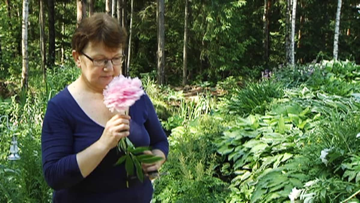 Nainen haistaa suurta kukkaa.