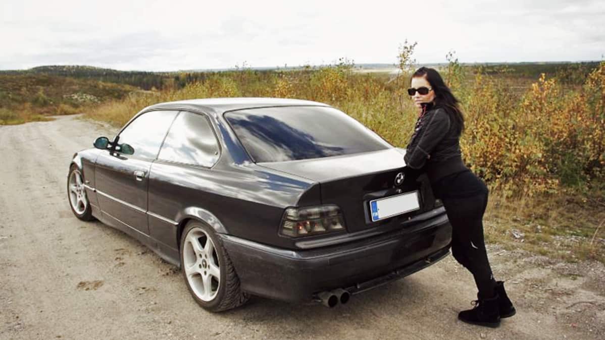 Anu Kovalainen poseeraa bemarinsa kanssa.