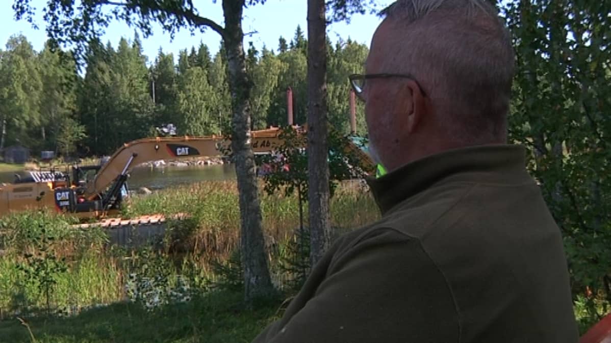Rainer Pendolin katselee kaapelin asennusta mökkinsä pihamaalta