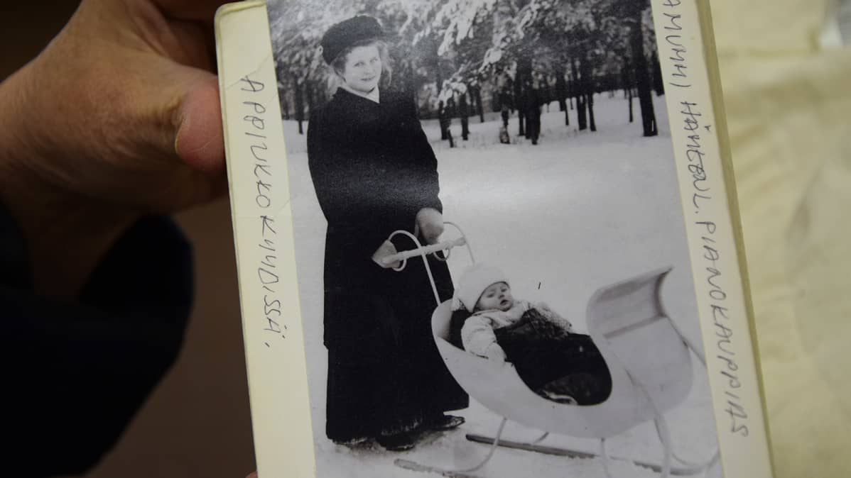 Kädessä albumi, jossa mustavalkokuva naisesta lapsen kanssa talvella