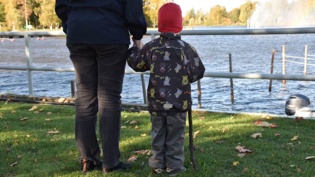 Lapsi ja aikuinen katsovat joelle.