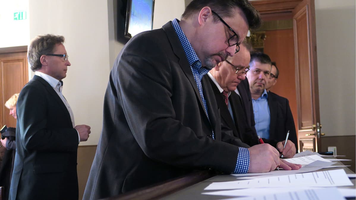 Miehet allekirjoittamassa aiesopimusta valtuustosalissa