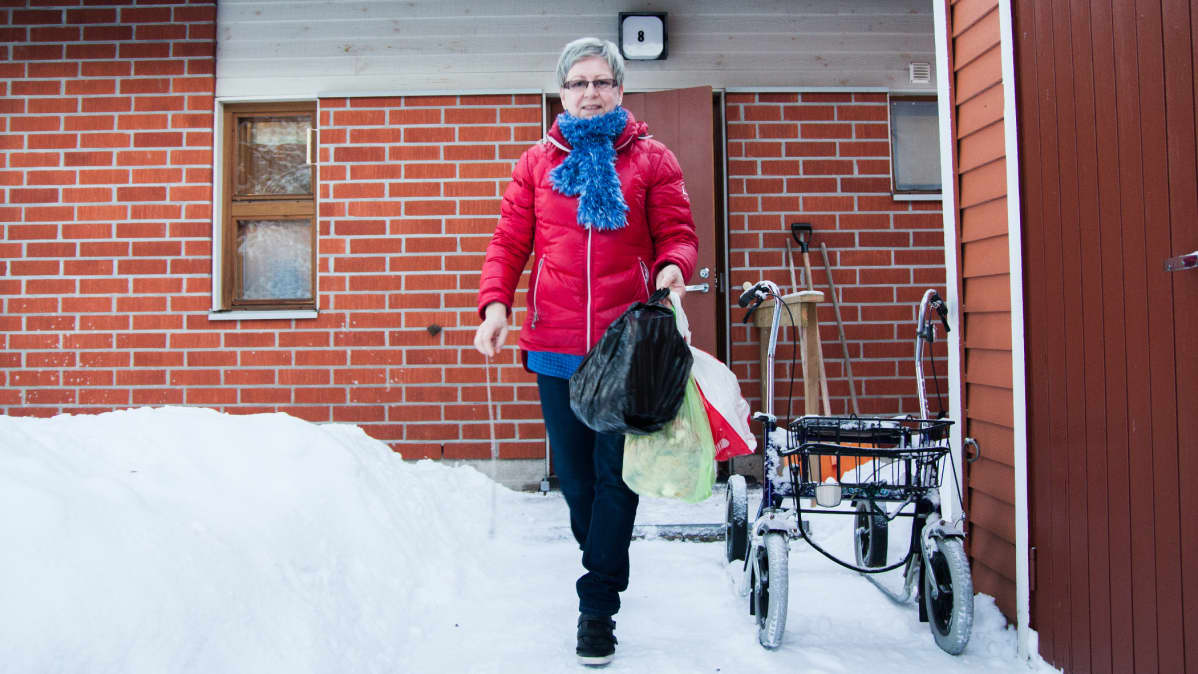 Kotihoitaja Paula Keränen vie asiakkaan roskia Hyrynsalmella.