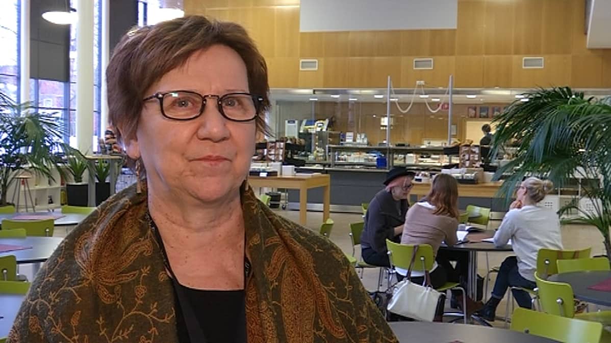 Silmälasipäinen nainen seisoo ruokalassa